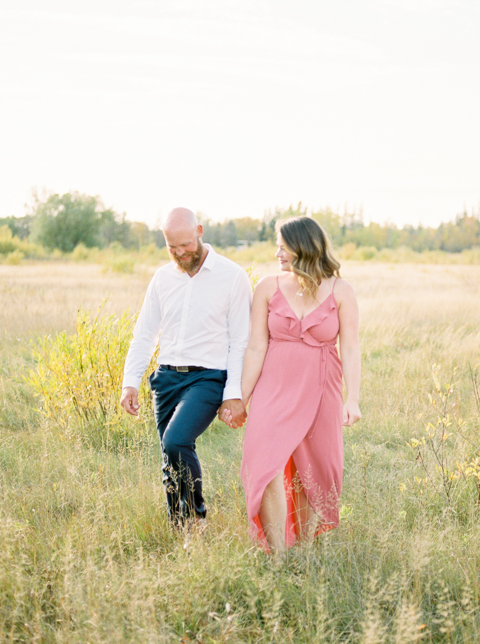 Fine Art Wedding Photographer Esther Funk Photography | A Semi Formal Birds Hill Provincial Park Engagement Session | A couple walking in the Prairies | What to wear to an Engagement Session | She is wearing a rose coloured dress