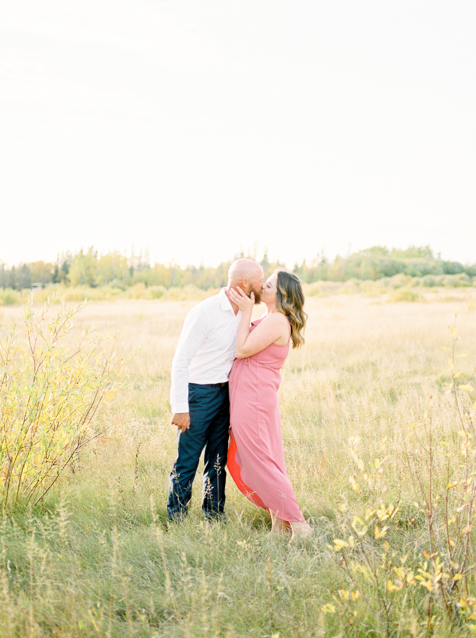 Fine Art Wedding Photographer Esther Funk Photography | A Semi Formal Birds Hill Provincial Park Engagement Session | A couple kissing in a field | She is wearing a rose coloured dress