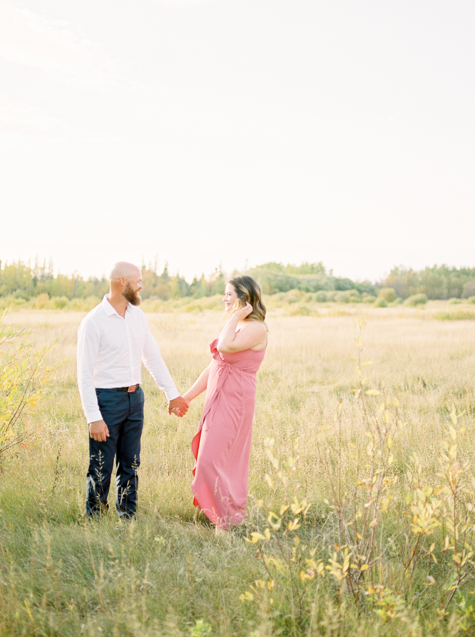 Fine Art Wedding Photographer Esther Funk Photography | A Semi Formal Birds Hill Provincial Park Engagement Session | A couple standing in a field | She is wearing a rose coloured dress